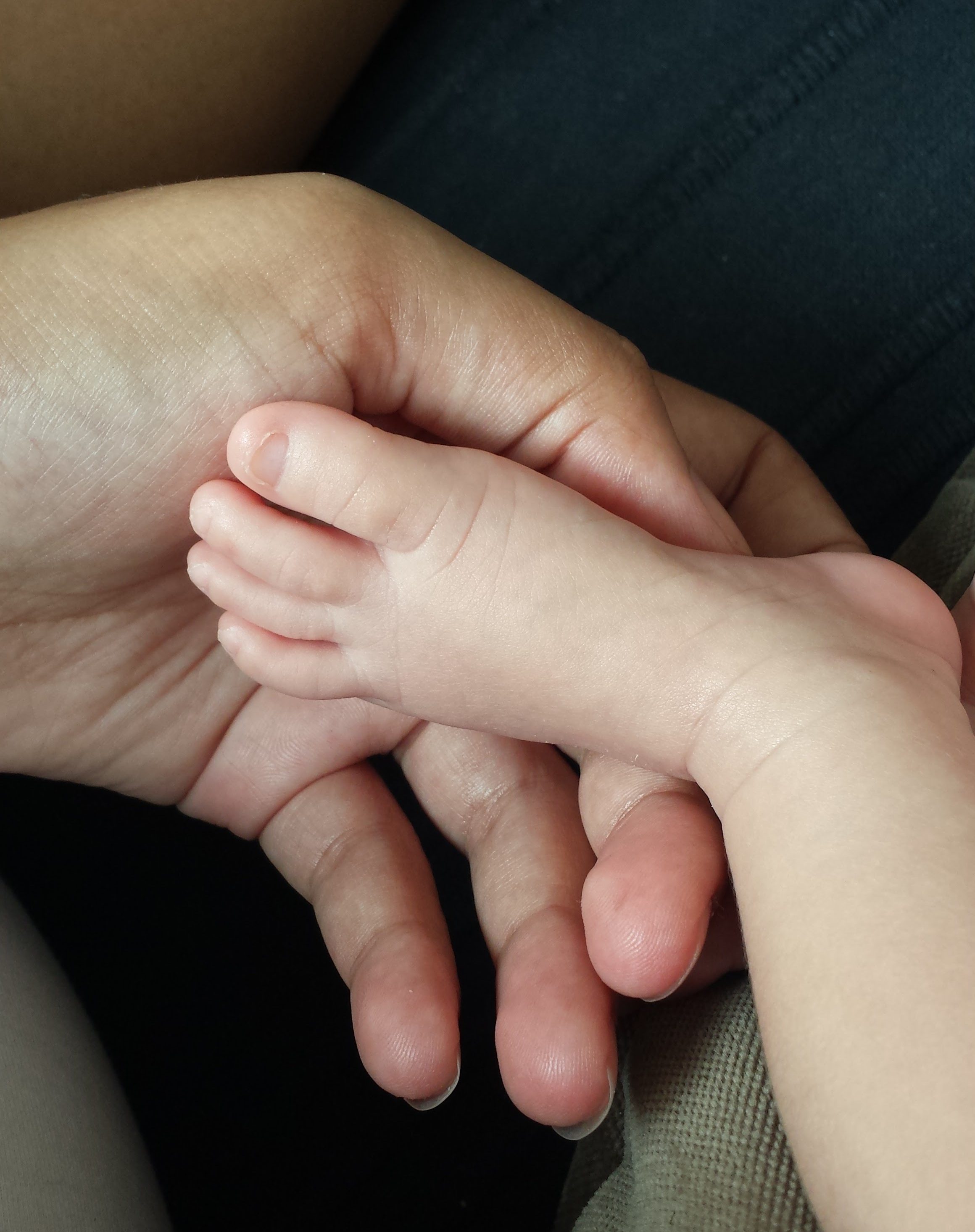 Petits pieds de bébé dans les mains d’un parent lors d’un moment de douceur